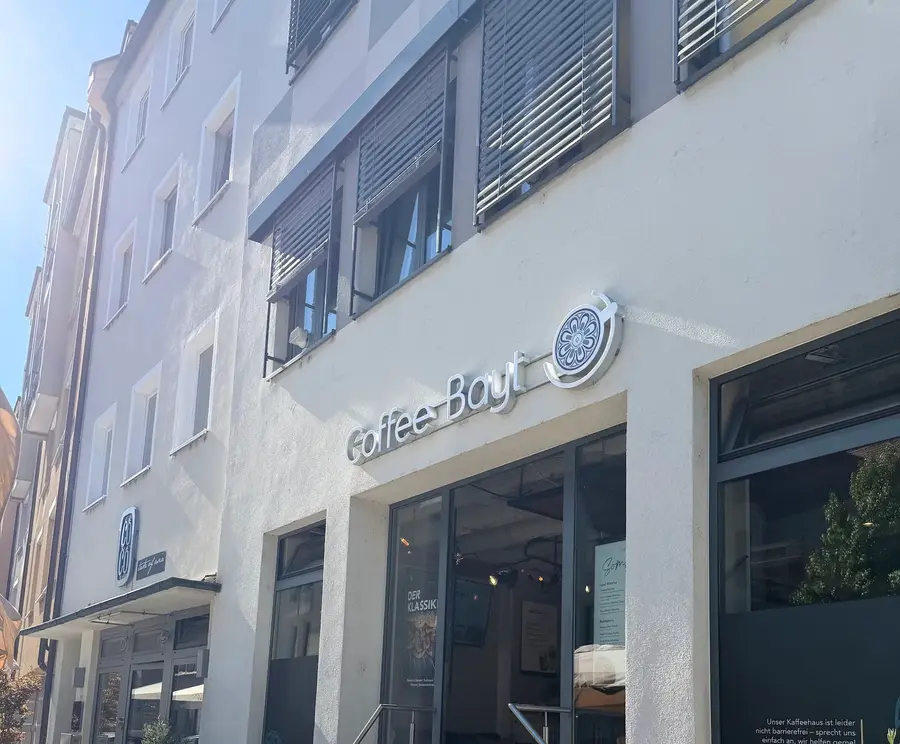 Die helle Fassade mit dem Coffee-Bayt-Schild und Stufen zum Eingang
