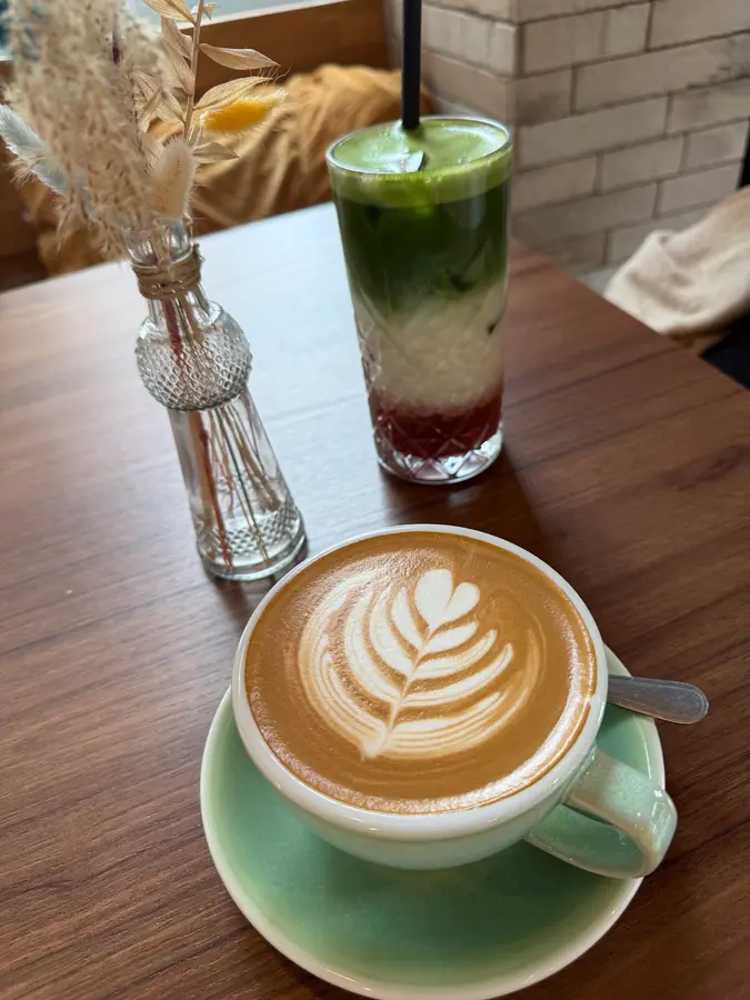 Geschichteter Matcha-Drink und Cappuccino mit Latte Art