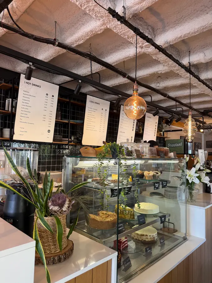 Theke mit Kuchenvitrine, Menütafeln und Glühbirnen unter der Gewölbedecke